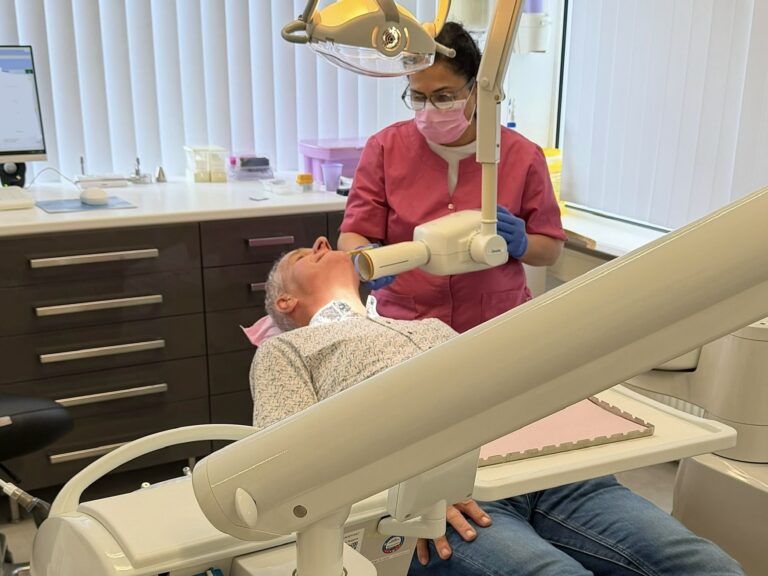 Dental hygienist at Shiny Smile Dental Clinic examining a patient's teeth in the treatment room